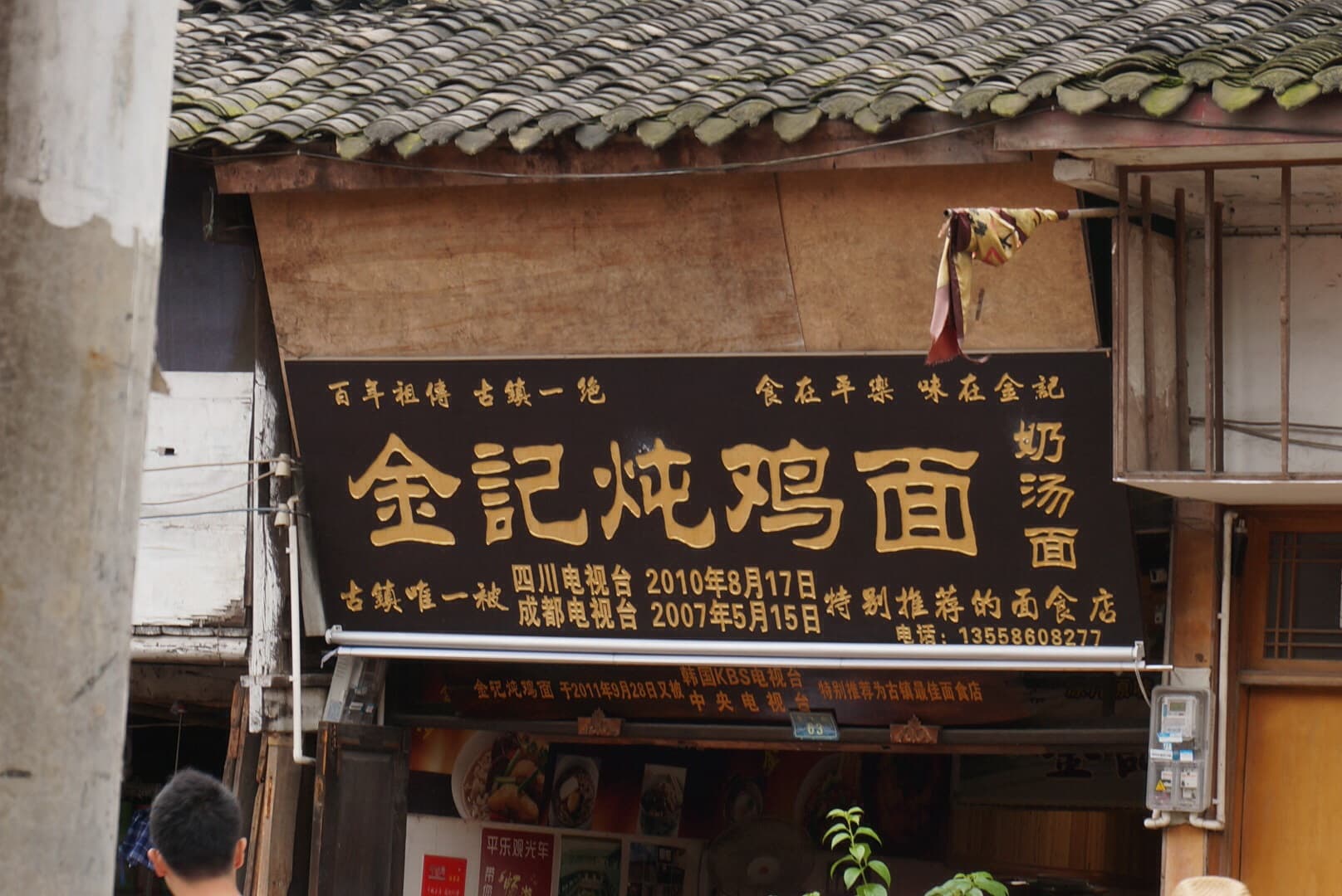 A chinese noodle shop which has a sign written in simplified and traditional chinese characters.